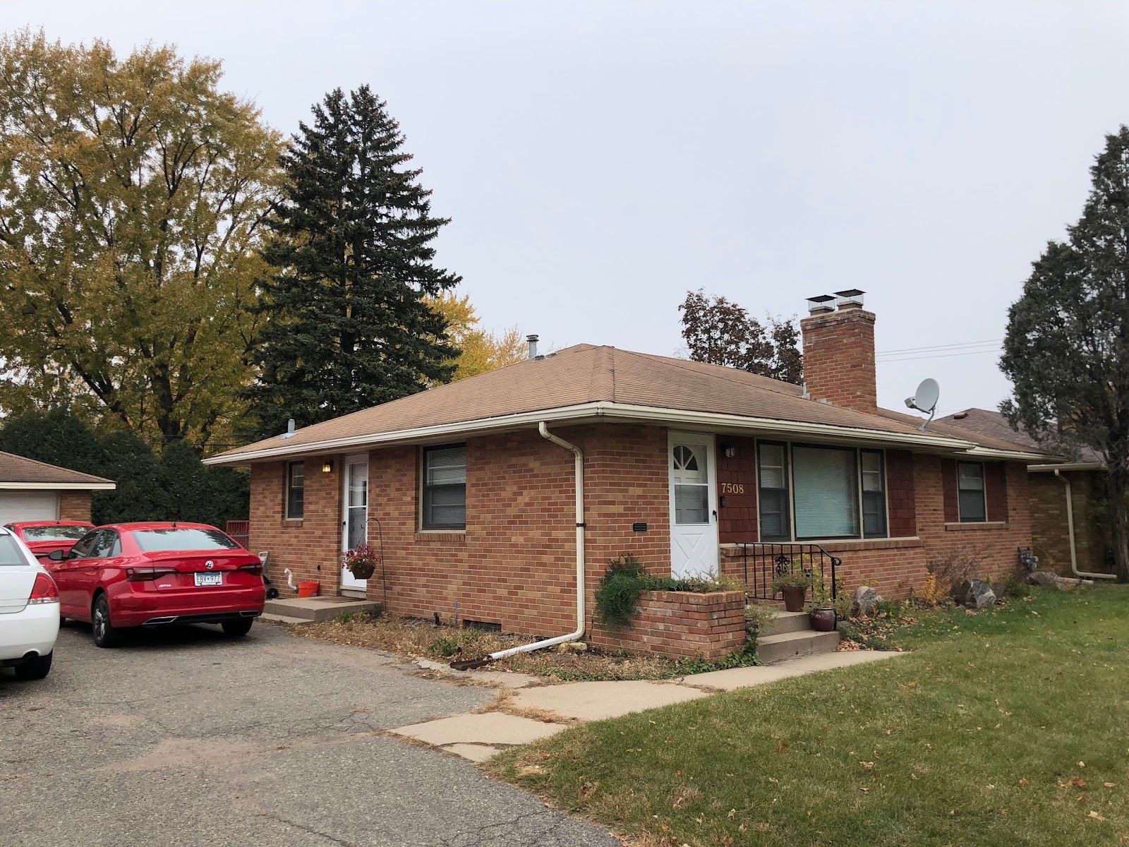 Tan shingle hip roof and brick chimney on a single-story brick home