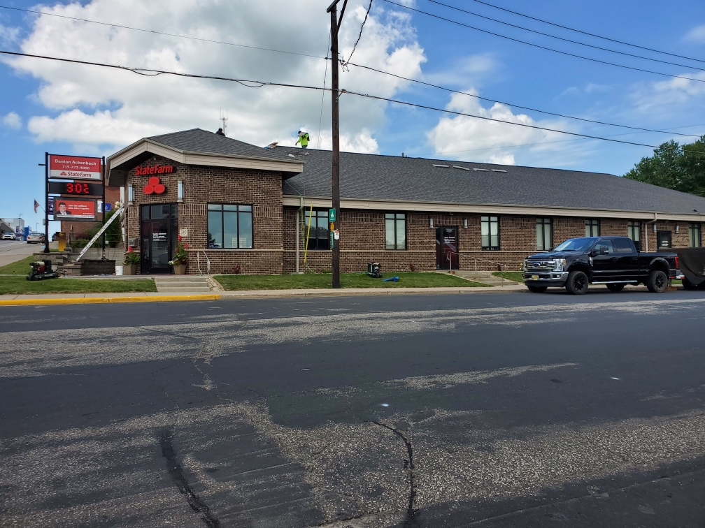 Roofing crew on the shingle roof of a brick commercial building