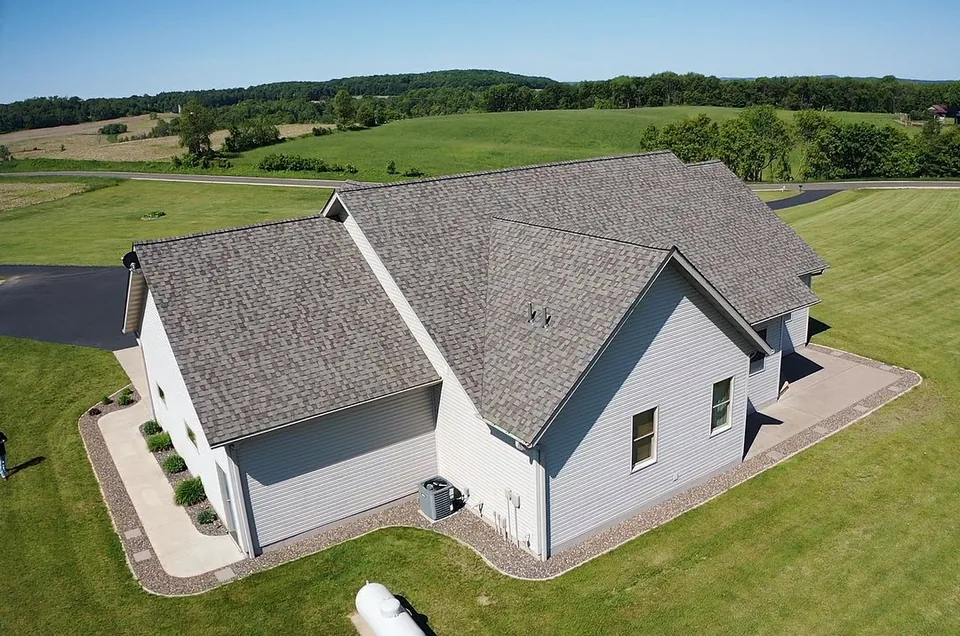 Completed shingle roof on a gray home by Level Edge Construction