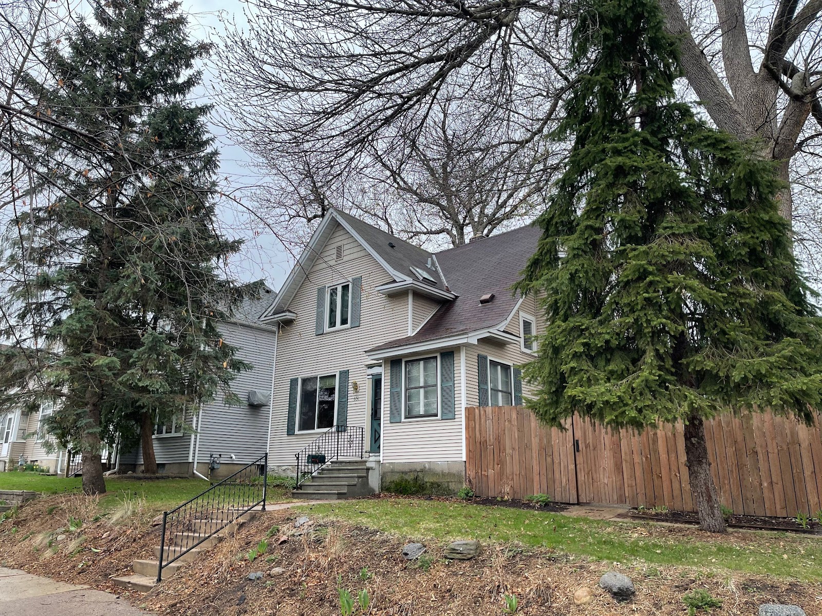 Completed shingle roof on a light-sided two-story home beside mature trees